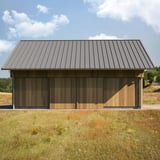 Verlegung von Stehfalzblech 33/500-LR Graualuminium auf einem Dach einer Holzscheune in ländlicher Umgebung