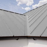 Verlegung von Stehfalzblech 33/500-LR in Weißaluminium RAL 9006 auf einem Dach mit Dachrinne
