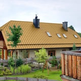 Grosses Haus mit sandgelbem Stehfalzblechdach PD-510-S Flach, mit Gauben und Dachfenstern