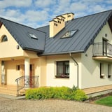 Stehfalzblech PD-510-S Flach Fehgrau auf einem Hausdach mit Gauben und Schornsteinen