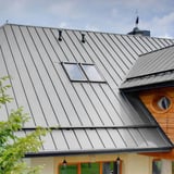Stehfalzblech PD-510-S Flach Lichtgrau auf einem Hausdach, Detailansicht mit Dachfenster