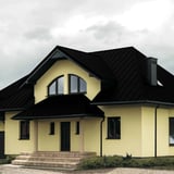 Stehfalzblech PD-510-S Tiefschwarz auf dem Dach eines Einfamilienhauses mit Gauben und Veranda