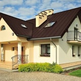 Stehfalzblech PD-510-S Mikro Schokoladenbraun (RAL 8017) auf einem Wohnhaus mit Gauben und Dachfenstern