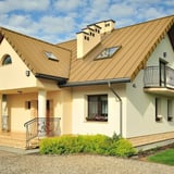 Stehfalzblech PD-510-S Mikro Sandgelb auf einem Wohnhaus mit Dachfenstern und Schornsteinen