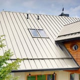 Stehfalzblech PD-510-S Mikro Reinweiß auf einem Dach mit zwei Dachfenstern und Holzverkleidung