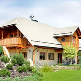 Stehfalzblech PD-510-S Mikro Reinweiß auf einem großen Wohnhaus mit Holzbalkon und Garten