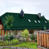 Stehfalzblech PD-510-S Mikro Gruen auf einem Wohnhaus mit Dachfenstern und Schornsteinen im Garten