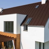 Stehfalzblech PD-510-S Mikro Schokoladenbraun RAL 8017 auf einem Hausdach mit weisser Fassade