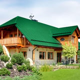 Haus mit Dach aus minzgrünem Stehfalzblech PD-510-S Mikro, Holzfassade und Balkon