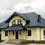 Stehfalzblech PD-510-S Mikro Fehgrau auf einem Wohnhaus mit gelber Fassade