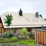 Stehfalzblech PD-510-S Mikro in Reinweiß auf einem Landhausdach mit Schornsteinen und Dachfenstern