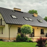 Stehfalzblech PD-510-S Mikro Graualuminium auf einem Wohnhausdach mit mehreren Dachfenstern