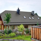 Stehfalzblech PD-510-S Mikro Graualuminium auf einem Wohnhausdach mit Gauben und Schornstein