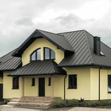Stehfalzblech PD-510-S Mikro Graualuminium auf einem Wohnhausdach mit Gauben und Schornstein
