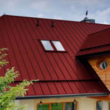 Stehfalzblech PD-510-S Kirschrot auf einem Dach mit zwei Dachfenstern und Holzverkleidung