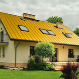 Wohnhaus mit Stehfalzblech PD-510-S Dach in Rapsgelb (RAL 1021) und mehreren Dachfenstern