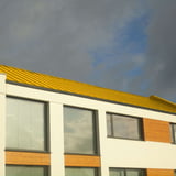Oberer Teil eines Hauses mit Stehfalzblech PD-510-S Dach Rapsgelb (RAL 1021) und Fenstern