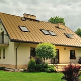 Stehfalzblech PD-510-S Sandgelb auf einem Wohnhaus mit mehreren Dachfenstern, Verlegung