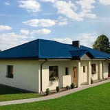 Einfamilienhaus mit Stehfalzblech PD-510-S Dach in Enzianblau (RAL 5010) und grossem Garten