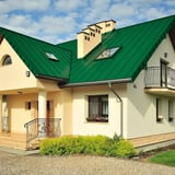 Minzgrünes Stehfalzdach auf einem Einfamilienhaus mit Gauben und Dachfenstern, sonniger Tag
