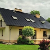 Haus mit Dach aus Stehfalzblech PD-510-S Graphitgrau, mit mehreren Dachfenstern