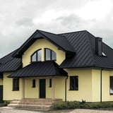 Haus mit Dach aus Stehfalzblech PD-510-S Graphitgrau, mit Gauben und dunklen Fenstern