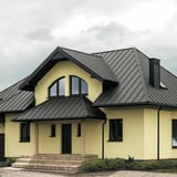 Stehfalzblech PD-510-S Graualuminium auf einem Hausdach mit dunklen Fenstern und Tuere