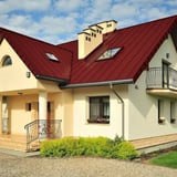 Stehfalzblech PD-510-S kirschrot auf einem Wohnhaus mit Dachfenstern, Verlegung am Dach
