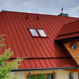Stehfalzblech PD-510-S korallenrot auf einem Wohnhaus mit Dachfenstern und Holzelementen