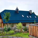 Stehfalzblech PD-510-S Enzianblau auf einem Wohnhaus mit Garten und Schaukel