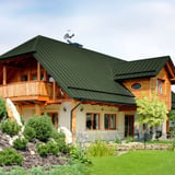 Haus mit Stehfalzblech PD-510-S in Chromoxidgrün, 0,50 mm Stahl, mit Holzbalkon und Garten