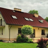 Stehfalzblech PD-510-S Nano, rotbraun, auf einem Wohnhaus mit Dachfenstern und Gauben