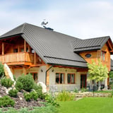 Stehfalzblech PD-510-S Graualuminium auf einem Hausdach mit Holzelementen und Garten