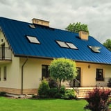 Stehfalzblech PD-510-S Trapez Enzianblau RAL 5010 auf einem Wohnhaus mit Garten
