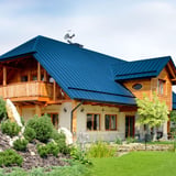 Stehfalzblech PD-510-S Trapez Enzianblau RAL 5010 auf einem Wohnhaus mit Holzfassade