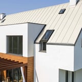 Stehfalzblech PD-510-S Reinweiß auf einem modernen Wohnhaus mit Dachfenstern und Holzelementen