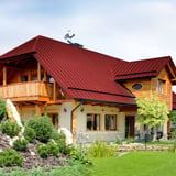 Stehfalzblech PD-510-S Kirschrot auf einem Wohnhaus mit Holzfassade und Garten