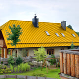 Haus mit Dach aus rapsgelbem Stehfalzblech PD-510-S Trapez, Ansicht von hinten mit Garten
