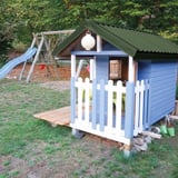 Trapezblech 20/1100 Dach in Chromoxidgrün auf einem blauen Kinderspielhaus mit Rutsche im Hintergrund