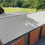 Trapezblech 35/207, Weißaluminium, auf einem Gebaeude mit roter Ziegelwand, Blick auf das Dach