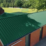 Trapezblech 35/207 Dach Moosgrün auf einem Gebäude neben einem Sportplatz