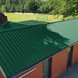 Trapezblech 35/207 Dach in Moosgrün auf einem Vereinsgebäude mit Ziegelschornstein