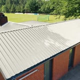 Trapezblech 35/207, Grauweiß, auf einem Gebäudedach mit Ziegelwand, Verlegung