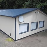 Trapezblech 35/207 Wand, Lichtgrau RAL 7035, an einer kleinen Halle mit dunklem Dach