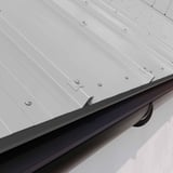 Traufenblech Weißaluminium (RAL 9006) montiert an einem Dach mit dunkler Dachrinne