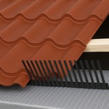 Traufenlüftungskamm aus schwarzem PVC unter roten Dachziegeln auf einer Dachkonstruktion