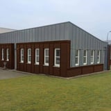 Gewerbegebäude mit Fassadenverkleidung aus nussbraunem Wellblech 18/1064 und grauen Paneelen