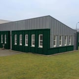 Moosgrünes Wellblech 18/1064 als Fassadenverkleidung an einem Industriegebäude mit vielen Fenstern
