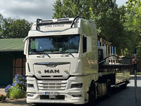 MAN-LKW liefert Dachbleche – Speditionsversand Weißer MAN-LKW mit Dachblechen bei der Anlieferung – Beispiel eines Speditionsfahrzeugs.