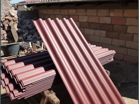 Stapel roter Faserzement Wellplatten, einsatzbereit für die Baustellenmontage